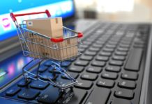 E-commerce. Shopping cart with cardboard boxes on laptop. 3d