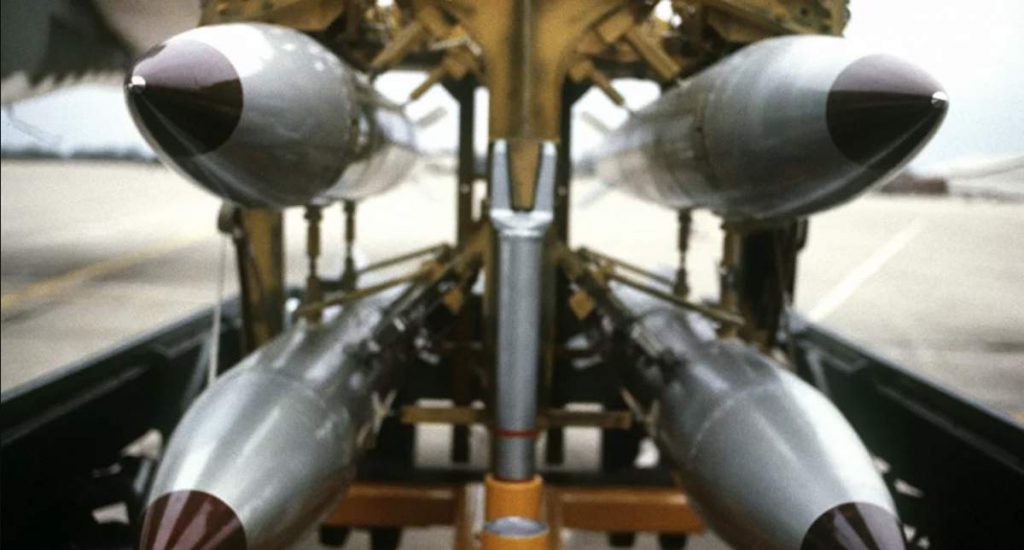 Visão frontal de quatro bombas nucleares de queda livre B-61 em um carrinho de bombas.